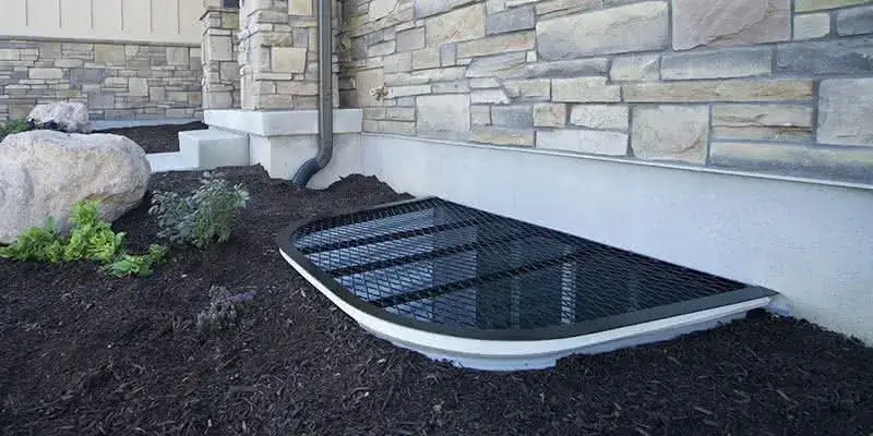 Custom window well cover installed in front of a home